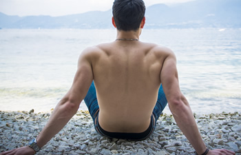 An inverted man sitting on the beach